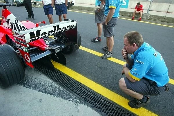 Formula One World Championship: A Renault mechanic takes a good look at the rear of the Ferrari F2002