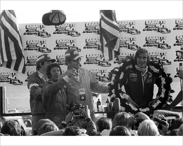 Formula One World Championship: Race winner James Hunt McLaren, watches third placed Mario Andretti Lotus, throw his cap to the fans on the podium