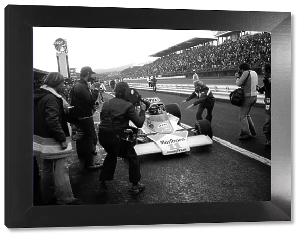 Formula One World Championship: At the end of the race Teddy Mayer, McLaren Team Manager, centre, attempts to slow down James Hunt, McLaren M23