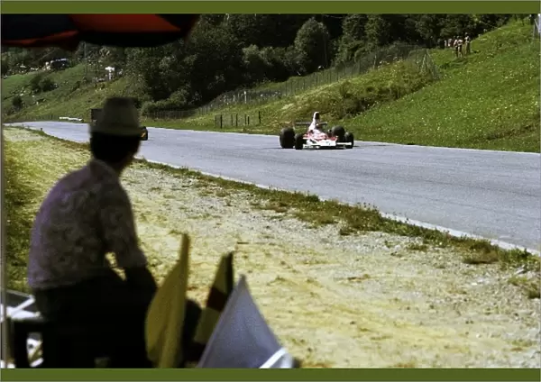 Formula One World Championship: A race marshal watches Emerson Fittipaldi McLaren M23, who retired on lap 38 with a blown engine, storm past him