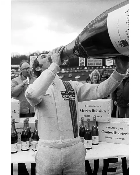 Non-Championship Formula One: John Watson Brabham, celebrates with a giant bottle of champagne after taking pole position for the race