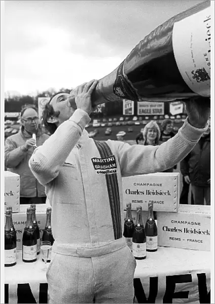 Non-Championship Formula One: John Watson Brabham, celebrates with a giant bottle of champagne after taking pole position for the race