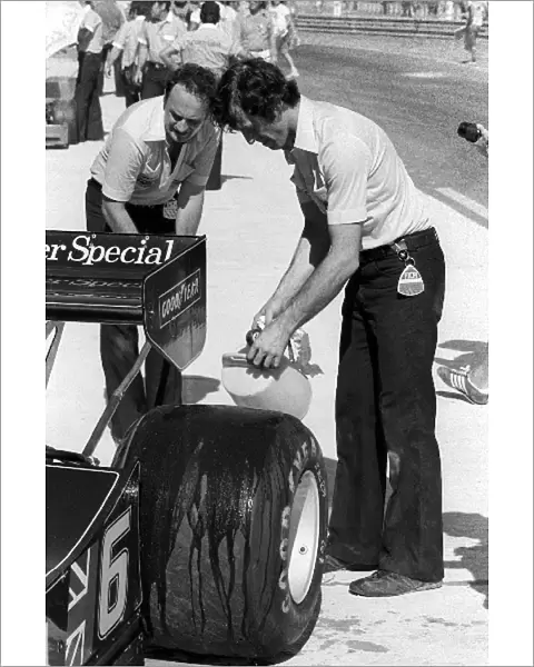Formula One World Championship: A Lotus mechanic pours water onto the rear tyre of the Lotus 78 of pole sitter Ronnie Peterson, who retired