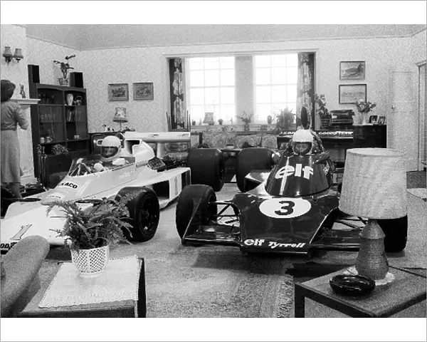 Formula One World Championship: A father and son sit in McLaren and Tyrrell F1 cars in their living room, possibly filming a television