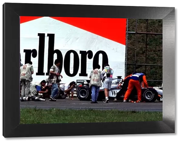 1998 BRAZILIAN GP. Photographers crowd round a stranded McLaren out on the track for