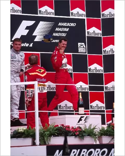 Formula One World Championship: Michael Schumacher Ferrari celebrates victory as David Coulthard McLaren and Jacques Villeneuve Williams accept