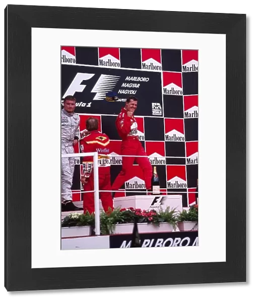 Formula One World Championship: Michael Schumacher Ferrari celebrates victory as David Coulthard McLaren and Jacques Villeneuve Williams accept