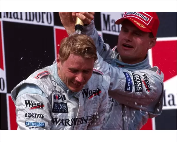 Formula One World Championship: The podium, race winner Mika Hakkinen McLaren, celebrates with second placed team mate David Coulthard McLaren
