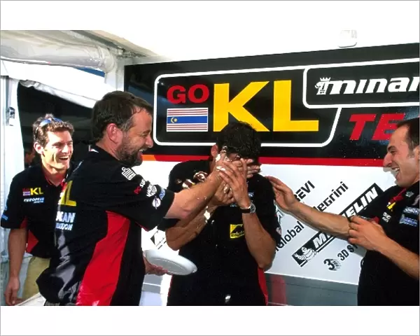 Formula One World Championship: Minardi team owner Paul Stoddart helps Alex Yoong celebrate his 26th birthday. Mark Webber, left, watches