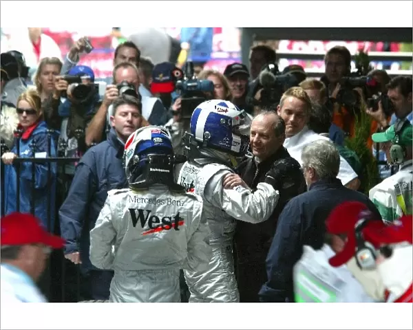Formula One World Championship: Third placed Kimi Raikkonen McLaren and race winning team mate David Coulthard McLaren are greeted in parc ferme