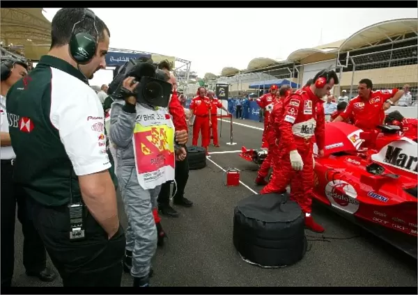 Formula One World Championship: Ben Agathangelou Jaguar Head of Aerodynamics has a look at the car of Michael Schumacher Ferrari F2004 on the grid