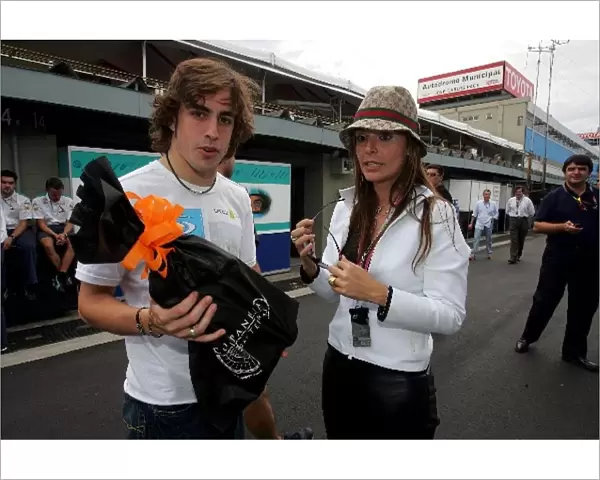 Formula One World Championship: Renata Borges girlfriend of footballer Roberto Carlos presents Fernando Alonso Renault with a bottle of Cachacha