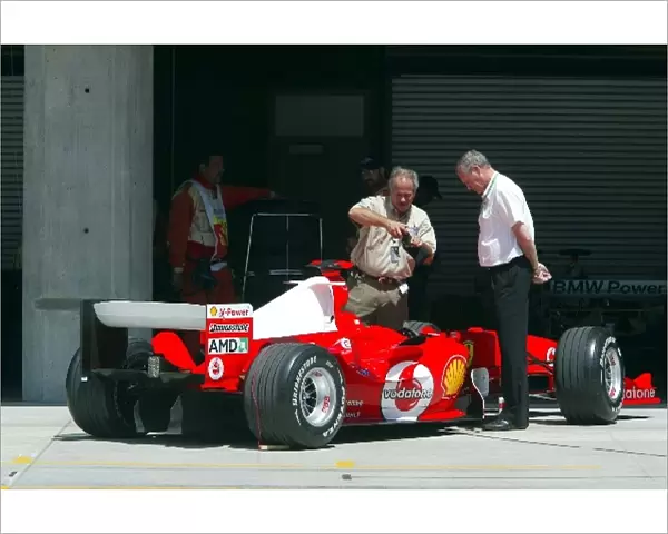 Formula One World Championship: Inquisitive pit lane marshals look at a Ferrari F2004