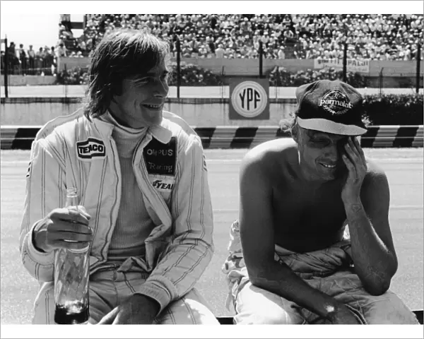 1979 Argentinian Grand Prix: James Hunt, retired, shares a joke with Niki Lauda, retired, in the pits, portrait