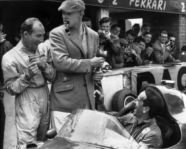 1958 British Grand Prix: Stirling Moss, retired, shares a joke with Mike Hawthorn, 7th position, in the pits with a mechanic, portrait