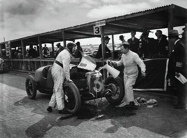 1926 British Grand Prix. Brooklands, Great Britain.7 August 1926. Gillow, George Eyston (Aston-Martin GP) mechanic, pouring water over the cars radiator in an endeavour to cool it. A blown-out gasket put this car out