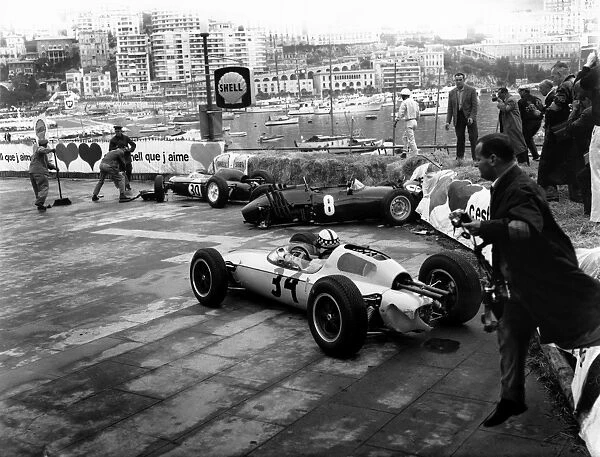 1962 Monaco Grand Prix: Innes Ireland, retired, avoids the wrecked cars of Richie Ginther and Maurice Trintignant, action