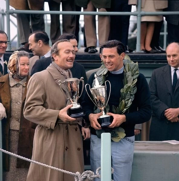 1964 Goodwood International Meeting: Jim Clark and Colin Chapman hold the News of the World winners trophies, portrait