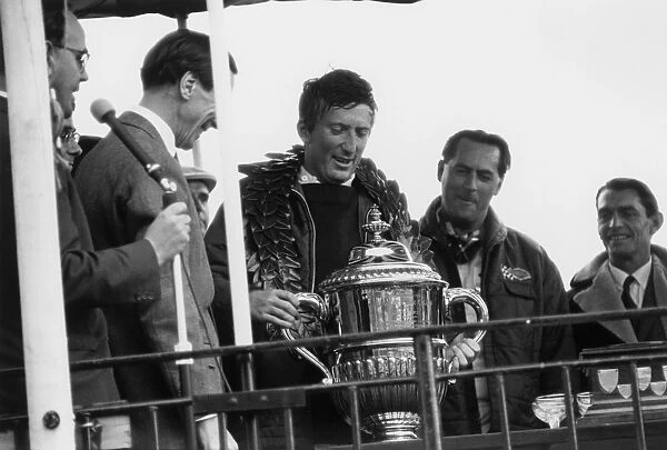 1966 Motor Show 200: Jochen Rindt, 1st position, lifts the winners trophy with Jack Brabham, 2nd position, on the podium, portrait