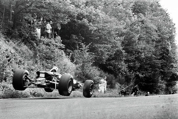 1967 German Grand Prix. Nurburgring, Germany. 4th - 6th August 1967. Jochen Rindt (Cooper T86-Maserati), retired, standing to the side, watching the cars get airborne at the Flugplatz section of the track, action