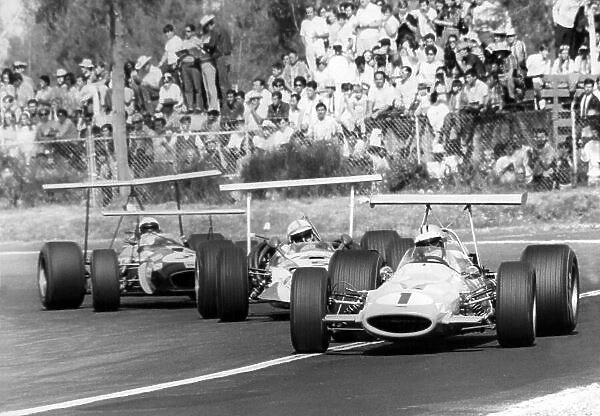 1968 Mexican Grand Prix. Mexico City, Mexico. 3 November 1968. Denny Hulme, McLaren M7A-Ford, retired, leads John Surtees, Honda RA301, retired, and Jack Brabham, Brabham BT26-Repco, 10th position