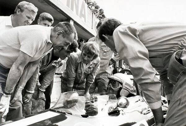 1969 Italian Grand Prix. Monza, Italy. 7 September 1969. Jack Brabham, Brabham BT26-Ford, retired, returned to racing at Monza. Here he talks to his engineers / mechanics including designer Ron Tauranac (left) and Ron Dennis (right), portrait