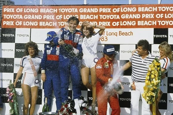 1983 United States Grand Prix West: John Watson, 1st position, celebrates on the podium with Niki Lauda, 2ndposition and Rene Arnoux, 3rd position