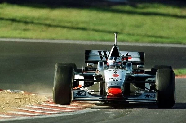 1997 LUXEMBOURG GP. MCLAREN MERCEDES DRIVER MIKA HAKKINEN BOUNCES OVER THE KERBS ON HIS WAY TO POLE POSITION FOR SUNDAY A GRAND PRIX. IT IS HIS FIRST POLE POSITION PHOTO: MARTYN ELFORD  /  LAT