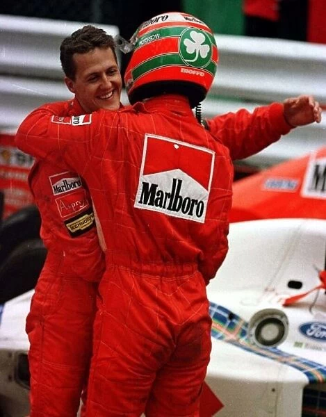 1997 MONACO GP. Michael Schumacher hugs Ferrari team mate Eddie Irvine after the team
