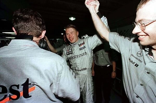 1998 BRAZILIAN GP. Mika Hakkinen celebrates with his team after securing another pole