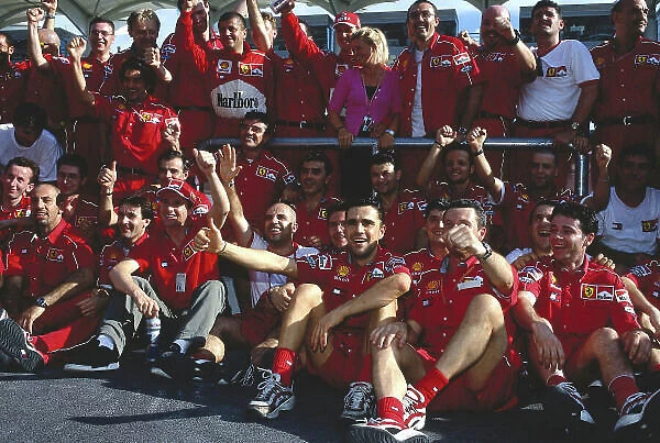 1999 Malaysian Grand Prix. Sepang, Kuala Lumpur, Malaysia. 15-17 October 1999. Eddie Irvine (front) celebrates his 1st position with the Ferrari team and team mate Michael Schumacher (with wife Corinna)