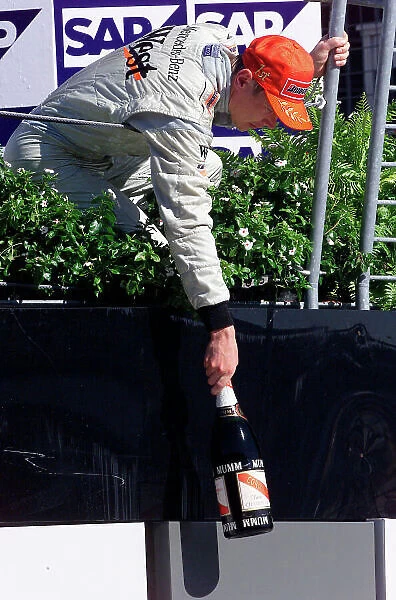 2001 American Grand Prix - Race Indianapolis, United States. 30th September 2001. Race winner Mika Hakkinen, West McLaren Mercedes MP4 / 16, hands down his champagne bottle to a member of the team. World Copyright