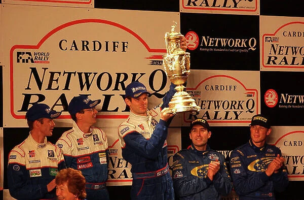 2001 FIA World Rally Championship. Rally of Great Britain. Cardiff, Wales. November 22-25, 2001. Marcus Gronholm holds the winner's trophy on the podium. Photo: Ralph Hardwick / LAT