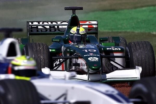 Australian GP: Luciano Burti Jaguar Cosworth R2 looks over at Ralph Schumacher as he cuts across the grass