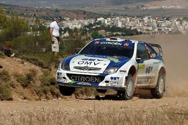 FIA World Rally Championship: Manfred Stohl, Citroen Xsara WRC, on Stage 3, with the town of Thiva in the background