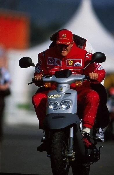 Formula One Testing: 2001 Formula One World Champion Michael Schumacher Ferrari takes his moped for a spin in the paddock