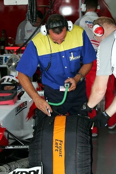 Formula One Testing: A Michelin engineer takes the temperature of a tyre on the car of Olivier Panis Toyota TF105