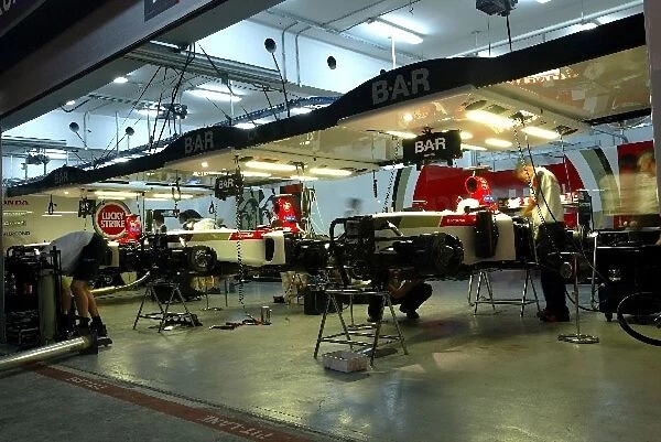 Formula One World Championship: BAR mechanics work on the cars in the garage into the night