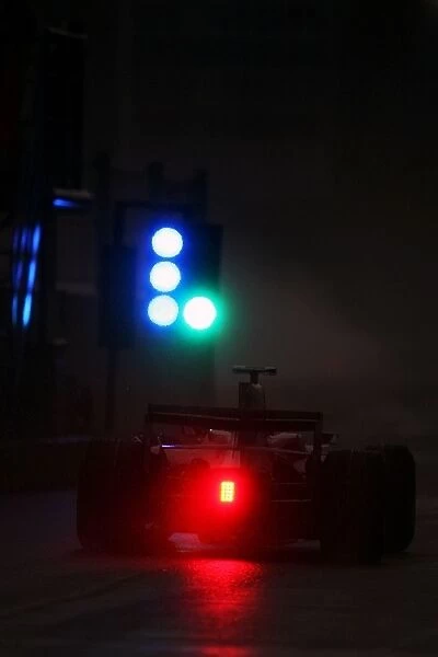 Formula One World Championship: A car leaves the wet and very dark pit lane