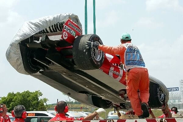 Formula One World Championship: The Ferrari F2004M of Rubens Barrichello is returned to the pits on a truck after he stopped on circuit during