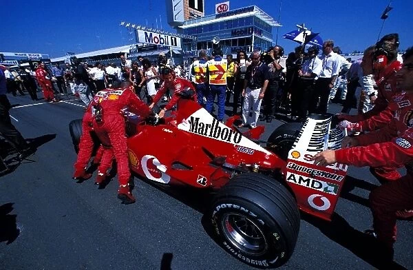 Formula One World Championship: Ferrari mechanics push a Ferrari F2002 onto the grid