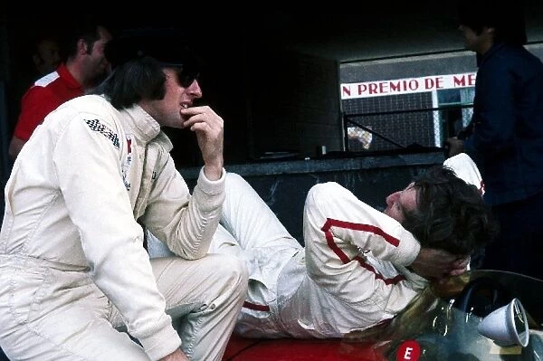Formula One World Championship: Fourth placed Jackie Stewart Matra, talks with race retiree Jochen Rindt Lotus as he relaxes on his Lotus 49B