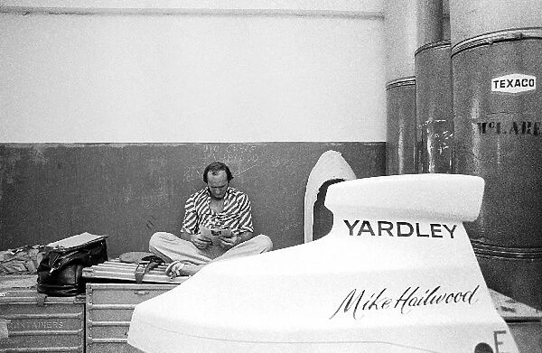 Formula One World Championship: Fourth placed Mike Hailwood McLaren relaxes reading a magazine in the McLaren garage