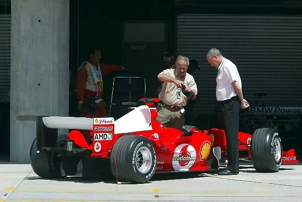Formula One World Championship: Inquisitive pit lane marshals look at a Ferrari F2004