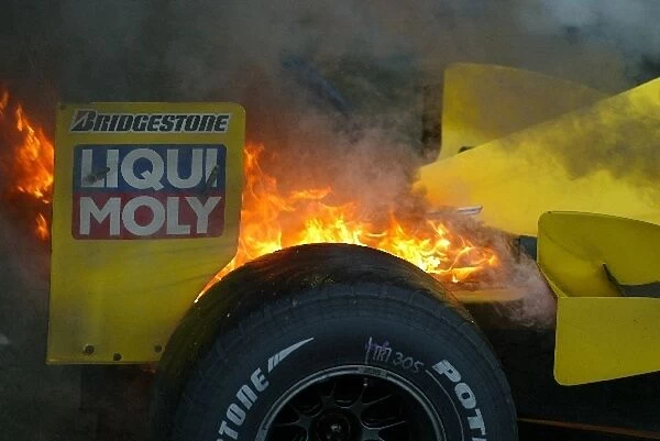 Formula One World Championship: The Jordan EJ13 of Giancarlo Fisichella bursts into flames as it arrives in Parc Ferme at the end of the shortened race