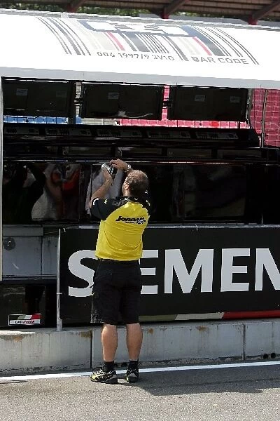 Formula One World Championship: A Jordan mechanic takes a cheeky snap of the BAR pit wall gantry