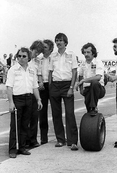 Formula One World Championship: Kenny Szymanski Lotus Tyre Mechanic and Clive Hicks with other Lotus mechanics in the pits