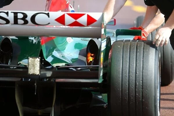 Formula One World Championship: Licks of flame from the Jaguar R5 of Mark Webber as he is pushed back in the pits