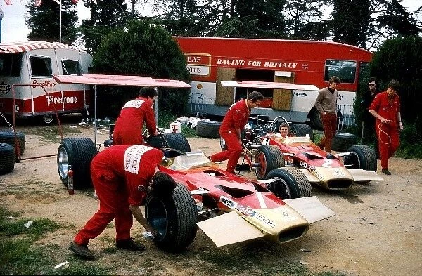 Formula One World Championship: The Lotus Cosworth 49Bs of Graham Hill and Jochen Rindt are prepared by mechanics in the primitive paddock
