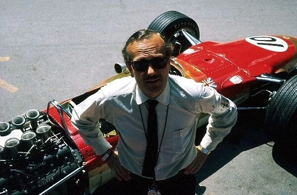 Formula One World Championship: Lotus team owner Colin Chapman poses with the Lotus Ford 49 of Jackie Oliver